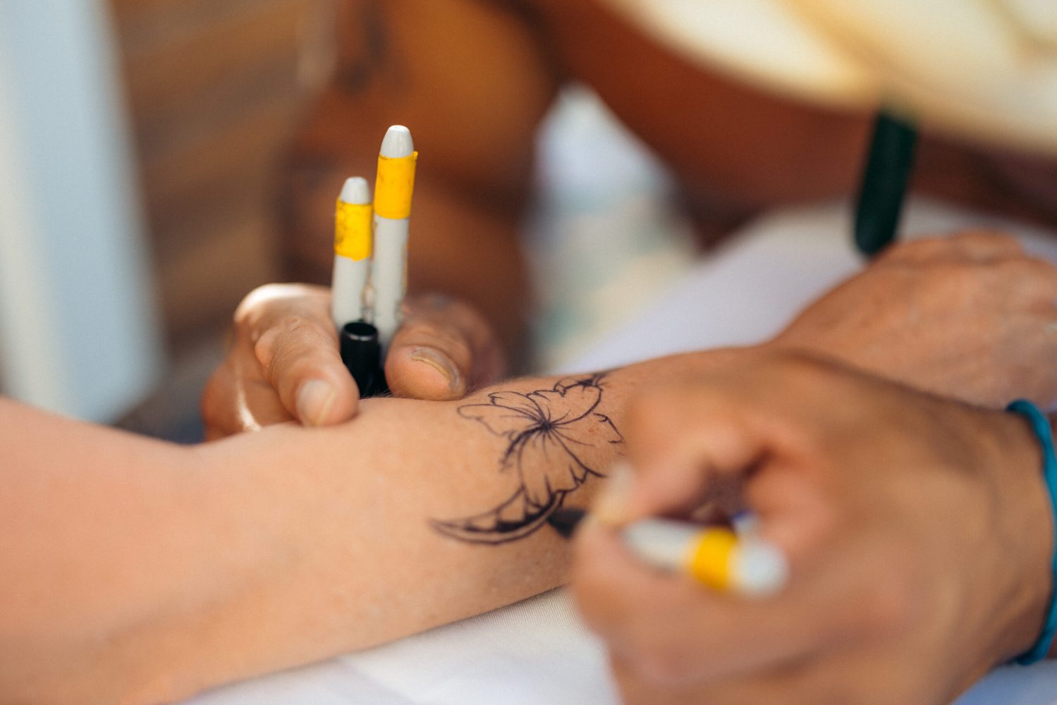 A tattoo being painted on a luau attendee