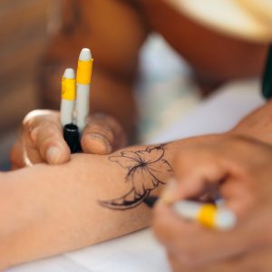 A tattoo being painted on a luau attendee